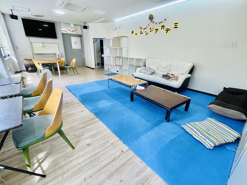 広場。テーブルとソファ、大きなモニターがあります